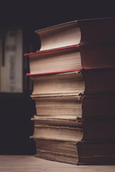 Stack of old books in front of book shelf