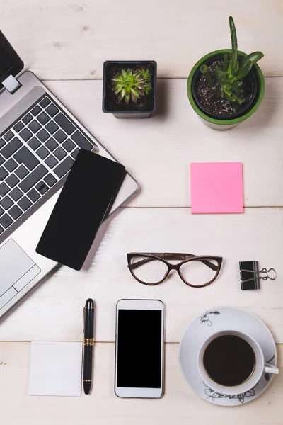 Modern office desk with laptop, phone and coffee