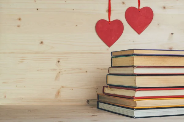 Books and hearts on a wooden background
