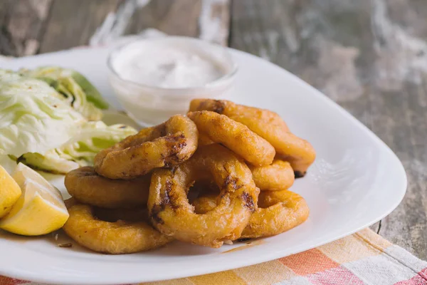 Fried squid circles with lemon and lettuce