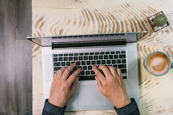 Above view of a man typing on a laptop keyboard