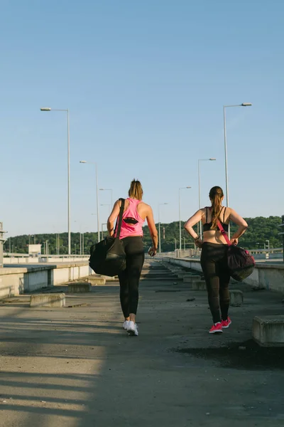 Two athlete females walking away after workout