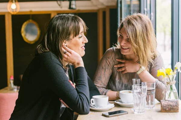 Two female friends drinking coffee and talking