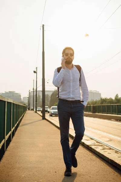 Man crossing railway bridge and talking on smart phone