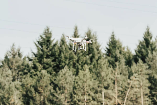 drone with camera flying above forest in sky