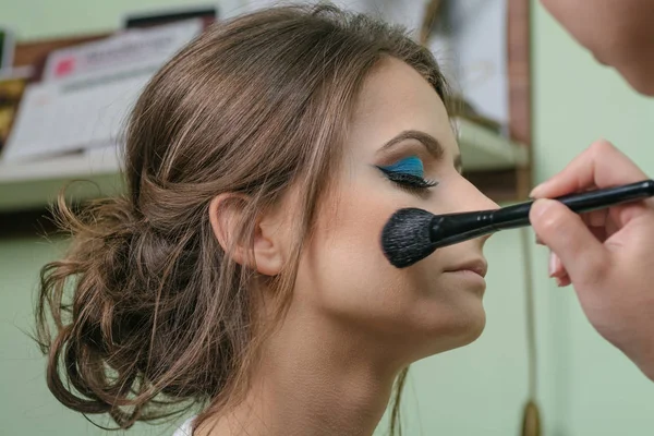 cropped shot of stylist applying makeup to beautiful young woman
