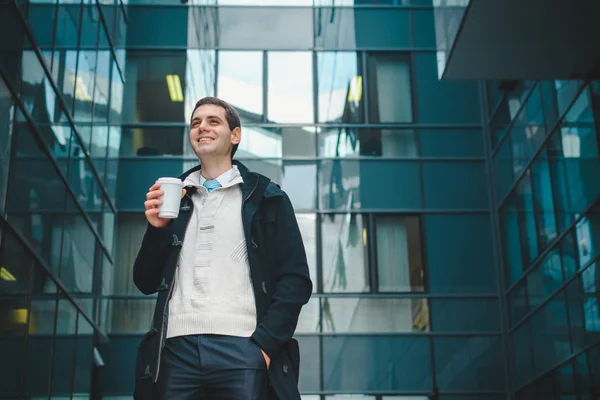 worker standing by office with coffee cup and smiling