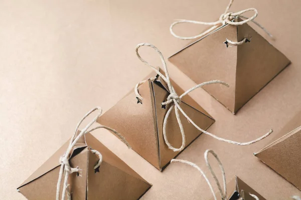 rows of handmade pyramid cardboard boxes with strings on beige background