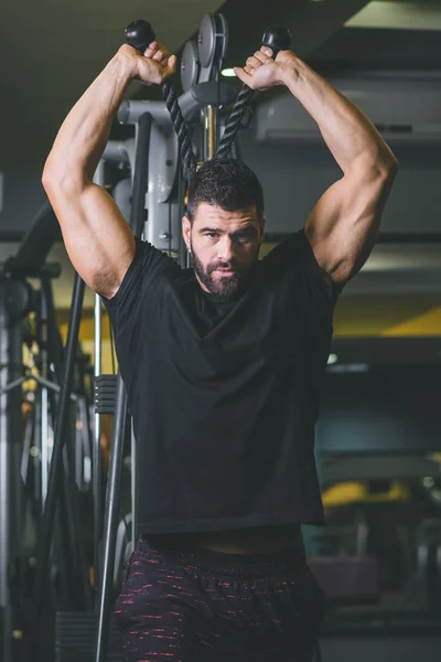 sportive man exercising on training apparatus with weight