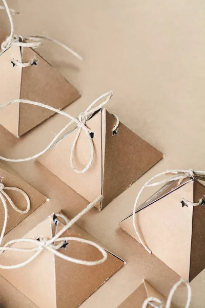 rows of handmade pyramid cardboard boxes with strings on beige background