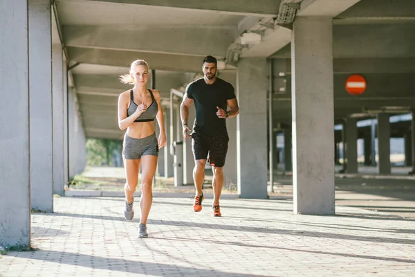 sportive woman and man jogging together in urban scene