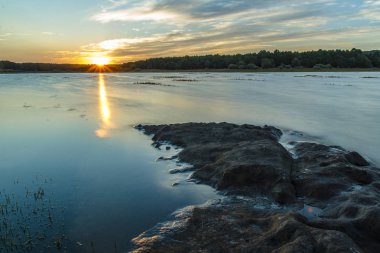 Rayo de sol refleja sobre el lago dibujando una llama apunto de Tocar la otra orilla