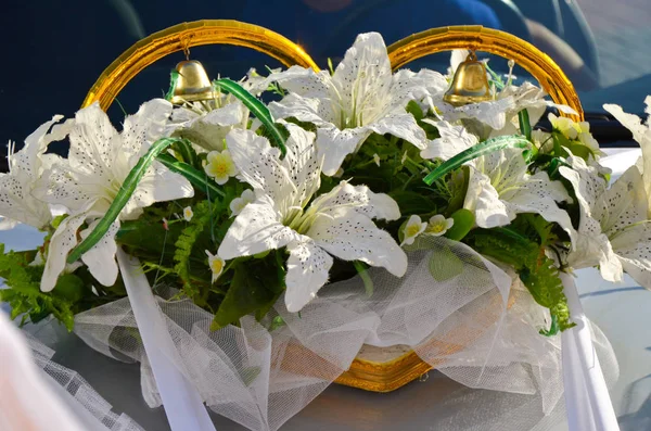 Wedding car decoration with white lilies and wedding rings