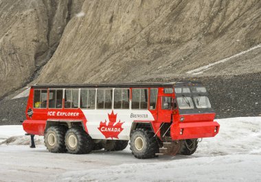 COLUMBIA ICEFIELD, ALBERTA, CANADA - JUNE 2018: Massive six wheel purpose-built tourist excursion vehicle stopped on the Athabasca Glacier in the Columbia Icefield in Alberta, Canada. clipart