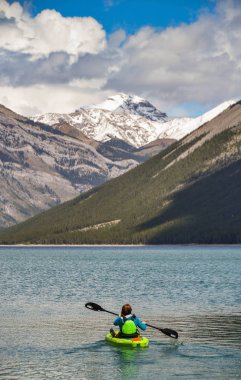Banff, Ab, Kanada - Haziran 2018: Lake Minnewanka Banff yakınındaki üzerinde küçük bir plastik kayık kürek çekmeye bir ziyaretçi doğal görünümünü.