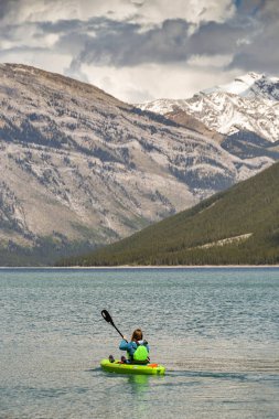 Banff, Ab, Kanada - Haziran 2018: Lake Minnewanka Banff yakınındaki üzerinde küçük bir plastik kayık kürek çekmeye bir ziyaretçi doğal görünümünü.
