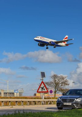 Londra - Kasım 2018: Londra Heathrow Havaalanı uyarı sürücülerin düşük uçan aircarft, A30 Road'da yol işareti. Arka planda bir n uçak lcoming gelecek.