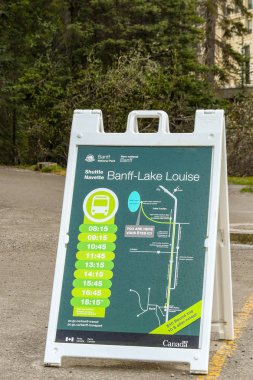 LAKE LOUISE, ALBERTA, CANADA - MAY 2018: Sign in the car park for Lake Louise showing visitors the timetable for the shuttle bus services to Banff. clipart