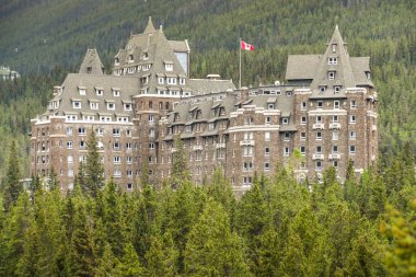Banff, Ab, Kanada - Haziran 2018: Banff Springs Fairmont Hotel yaprak dökmeyen ağaçları ile çevrili doğal görünümünü.