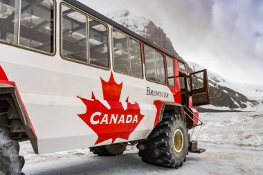COLUMBIA ICEFIELD, ALBERTA, CANADA - JUNE 2018: Large six wheel purpose-built vehicle which takes tourists onto the Athabasca Glacier in the Columbia Icefield in Alberta, Canada. clipart