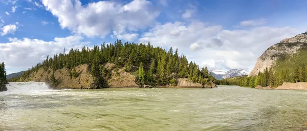 Panoramic view of the Bow River as it flows through Banff, Canada, with the Bow River Falls on the left.