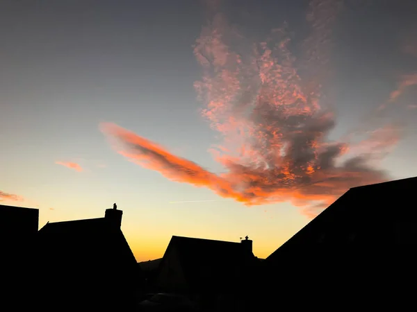 Houses silhouetted against a colourful sky at dawn