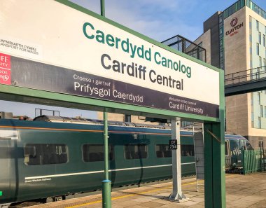 Cardiff, Galler - Aralık 2018: İstasyon adı işareti Cardiff Merkez İstasyonu'na. Great western tarafından işletilen bir Inter şehir tren demiryolu arka planda geçiyor.