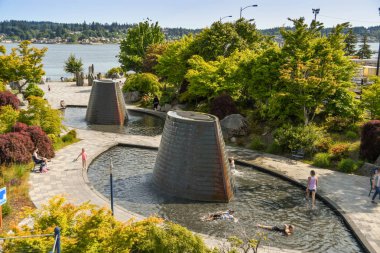 BREMERTON, WASHINGTON Eyaleti, ABD - HAZİRAN 2018: Gençler Bremerton, WA 'daki Harborside Fountain Parkı' nın su kefenlerinde oynuyorlar.