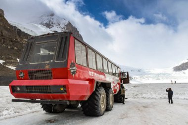 COLUMBIA ICEFIELD, ALBERTA, CANADA - JUNE 2018: Massive six wheel purpose-built vehicle which takes tourists onto the Athabasca Glacier in the Columbia Icefield in Alberta, Canada. clipart