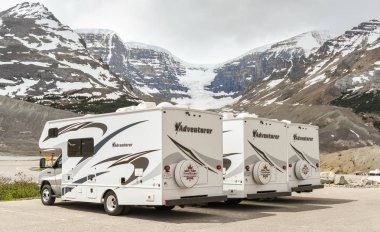 COLUMBIA ICEFIELD, ALBERTA, CANADA - JUNE 2018: Row of camper vans parked at the Columbia Icefield Visitor centre in Alberta, Canada. clipart