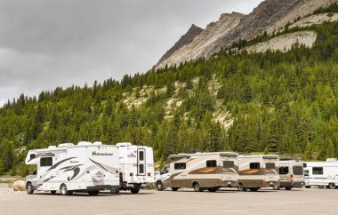 COLUMBIA ICEFIELD, ALBERTA, CANADA - JUNE 2018: Row of camper vans parked at the Columbia Icefield Visitor centre in Alberta, Canada. clipart
