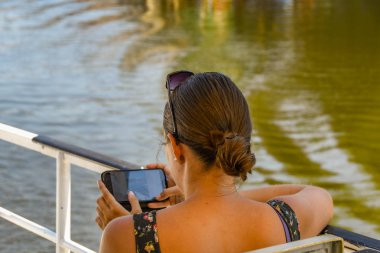 Prague, Çek Cumhuriyeti - Ağustos 2018: süre stitting alongisde bir nehir Prag şehir merkezinde bir cep telefonu resimleri kontrol kişi.