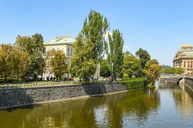 Prague, Çek Cumhuriyeti - Temmuz 2018: Prag Nehri Vltava kıyısına Park alanı ayarda Zofin konser salonunda bina. Ulusal Tiyatro Binası hakkıdır.