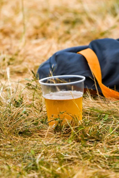 Disposable plastic cup of beer discarded on the grass at an outdoor event