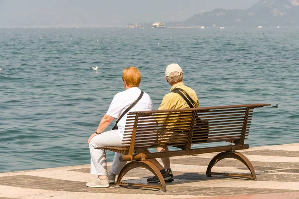 Lazise, Lake Garda, İtalya - Eylül 2018: Lake Garda Lazise sahil alanının bir bankta oturan iki kişi.