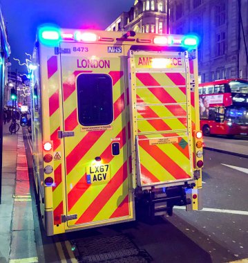 Londra - Aralık 2018: Acil bir çağrı merkezi Londra'da bir sokakta park Nhs ambulans mavi ışıkları yanıp sönen ile.