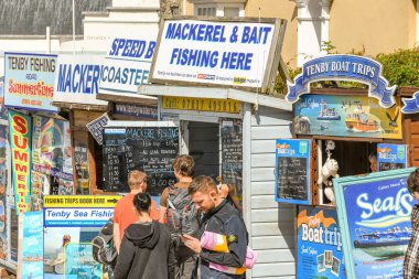 Tenby, Pembrokeshire, Galler - Ağustos 2018: işaretler ve Balık tutma turları ve tekne gezileri Tenby, Batı Galler yerel tekne operatörleri tarafından sunulan bilgi bakarak insanlar.