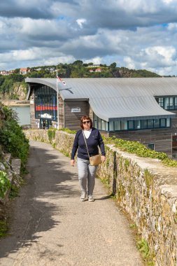 Tenby, Pembrokeshire, Galler - Ağustos 2018: Tenby, Batı Galler kıyı patika boyunca yürüyüş kişi. Arka planda yeni Rnli cankurtaran istasyonu bulunmaktadır.