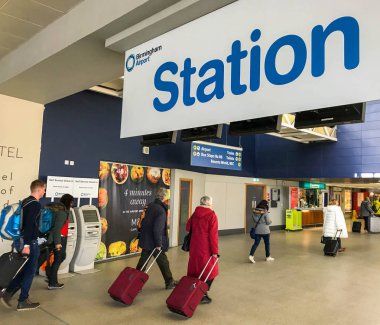 Havaalanından geldikten sonra Birmingham Uluslararası Tren istasyonuna giren bavul çeken insanlar
