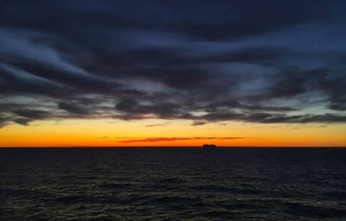 Denizde batımında ufukta cruise gemi