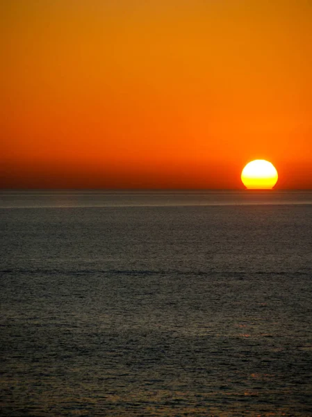 Sun setting on the horizon over a calm ocean