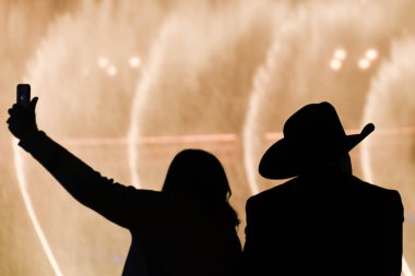 LAS VEGAS, BEVADA, ABD - Şubat 2019: Kovboy şapkalı bir adam ve Las Vegas 'taki Bellagio Oteli' nin çeşmelerine karşı selfie çeken bir kadın.