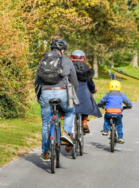 SWANSEA, WALES - OCTOBER 2018: Family cycling along the coastal path from Mumbles to Swansea. clipart