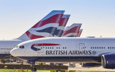 Londra, İngiltere-Mart 2019: İngiliz Airways tarafından işletilen Boeing 777 uzun mesafeli havayolu Londra Heathrow Havaalanı 'nda şirketin diğer uçağın kuyruk yüzgeçleri geçmiş almak için Taksilemek.