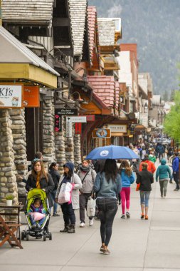 Banff, AB, Kanada-Haziran 2018: Banff merkezinde geçmiş dükkanlar gezinme turistler. Bir kişi bir şemsiye tutuyor.