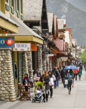 Banff, AB, Kanada-Haziran 2018: Banff merkezinde geçmiş dükkanlar gezinme turistler. Bir kişi bir şemsiye tutuyor.