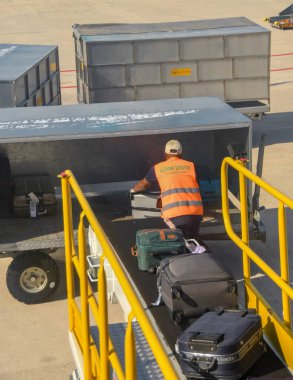 Verona, İtalya - Eylül 2018: Havaalanı çalışanı Verona havaalanında bavulları bagaj konveyör bandına yükleiyor