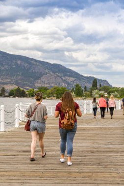 Kelowna, British Columbia, Kanada - Haziran 2018: Kelowna, British Columbia, Kanada'da Okanagan Gölü'nün kenarında yürüyen insanlar.