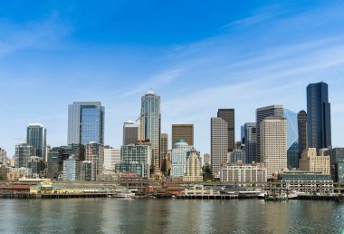 Seattle, Washington State, ABD - Haziran 2018: Puget Sound'dan bakıldığında Seattle şehir merkezindeki rıhtım ve ofis binalarının şehir manzarası.