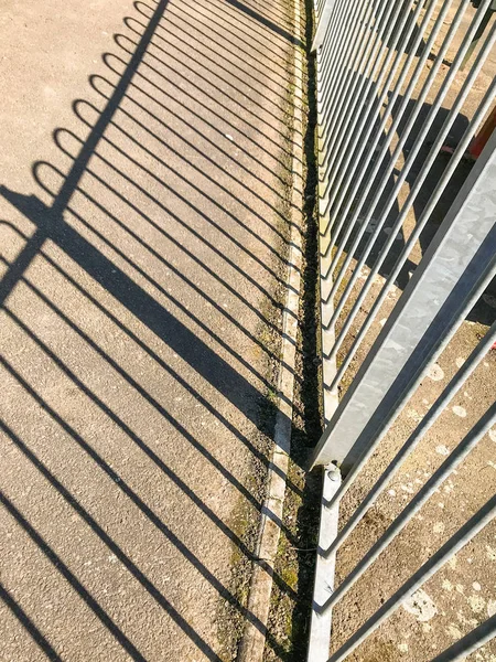 Black shadow cast on the ground by metal railings